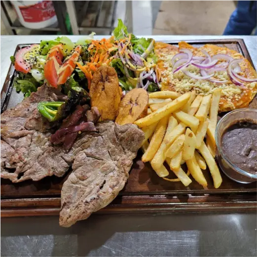 Plato fuerte con carne asada de primera calidad, papas fritas, ensalada y guarniciones en Restaurante Moyo en Martínez de la Torre.