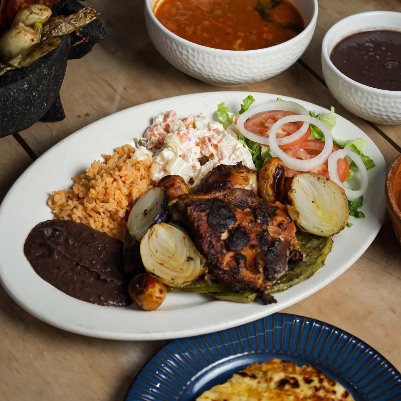 Platillo de tradicional pollo asado al carbón con arroz, frijoles, ensalada rusa y cebollitas asadas en Asadero Moyo, Martínez de la Torre.