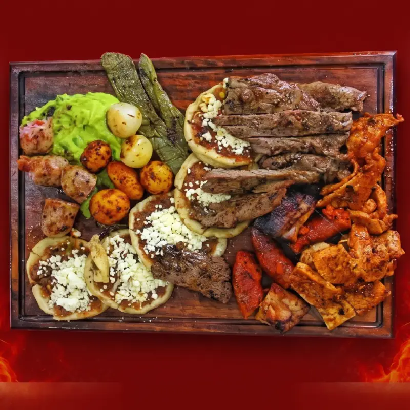 Tabla de madera con una abundante parrillada familiar que incluye cortes de res, carne adobada, salchichas, sopes con queso, guacamole, nopales y cebollitas asadas del restaurante Pollo Moyo en Martínez de la Torre.