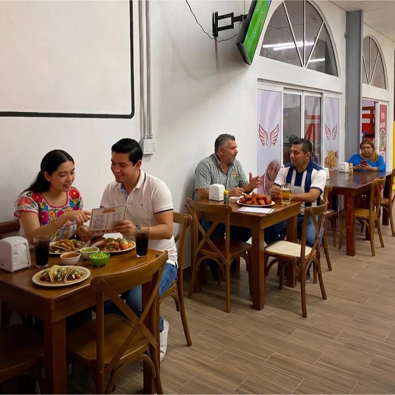 Familias y amigos compartiendo parrilladas, tacos y bebidas en el agradable ambiente del restaurante Taco Moyo en Martínez de la Torre.