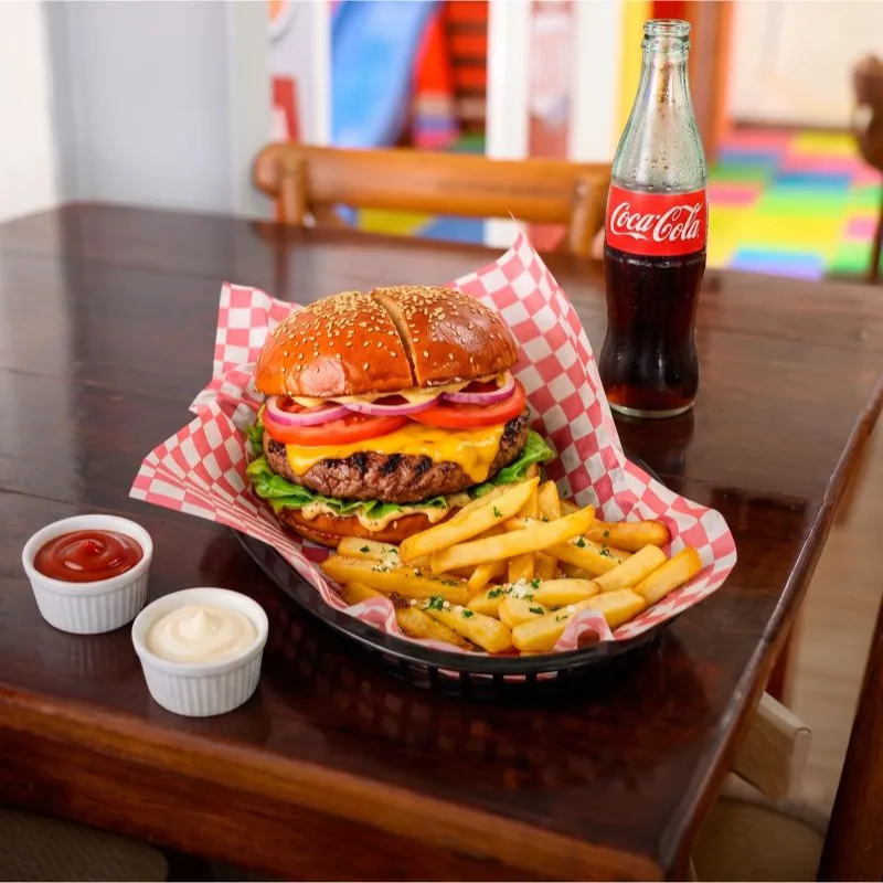 Hamburguesa jugosa con queso derretido, vegetales frescos y pan artesanal, servida con papas a la francesa en Taco Moyo, Martínez de la Torre.